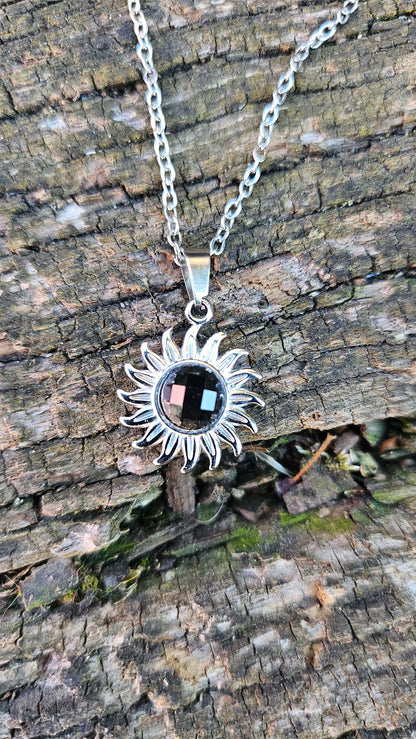 Le collier "Soleil" en obsidienne noire incarne une union parfaite entre élégance mystique et protection énergétique. Ce bijou remarquable présente un pendentif en forme de soleil, soigneusement sculpté dans de l'obsidienne noire, une pierre précieuse reconnue pour sa capacité à absorber les énergies négatives. Le design solaire symbolise la lumière et la force intérieure, tandis que l'obsidienne noire ajoute une touche de mystère et de profondeur. Ce collier, monté sur une chaîne en acier inoxydable hypoal